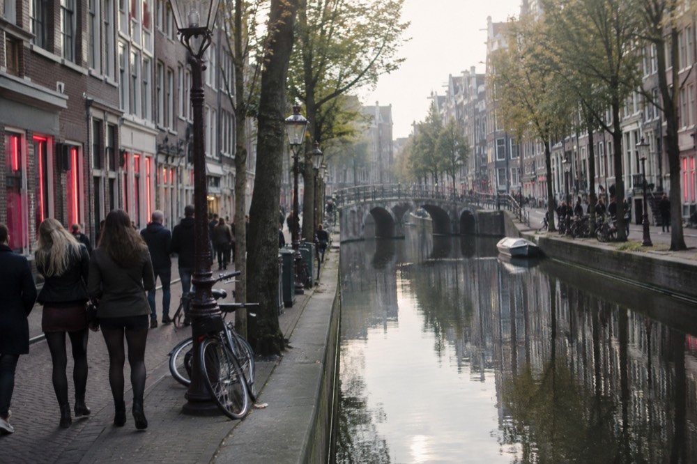 A narrow canal-side street with old brick buildings in central Amsterdam