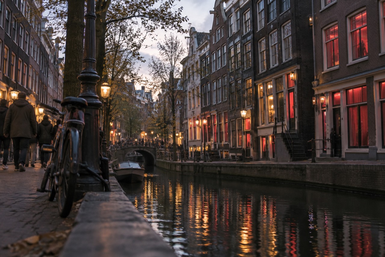 Canal houses and a narrow lit street in Amsterdam's old centre at dusk