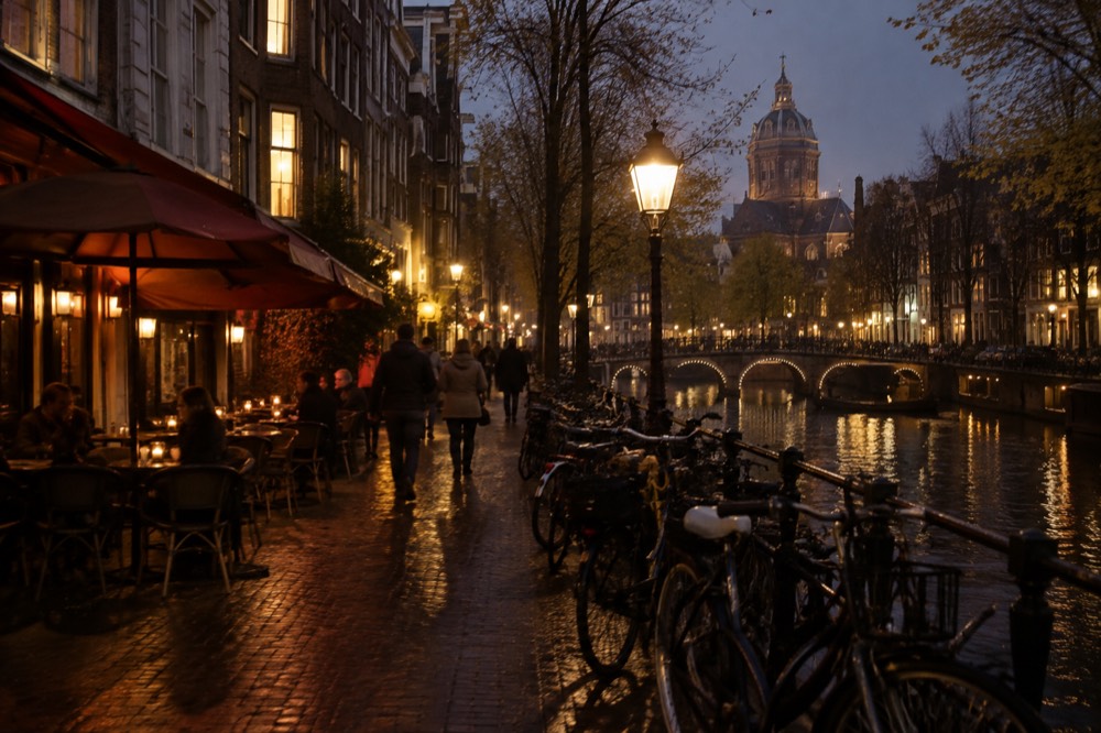 A canal-side street in central Amsterdam with café awnings and parked bicycles
