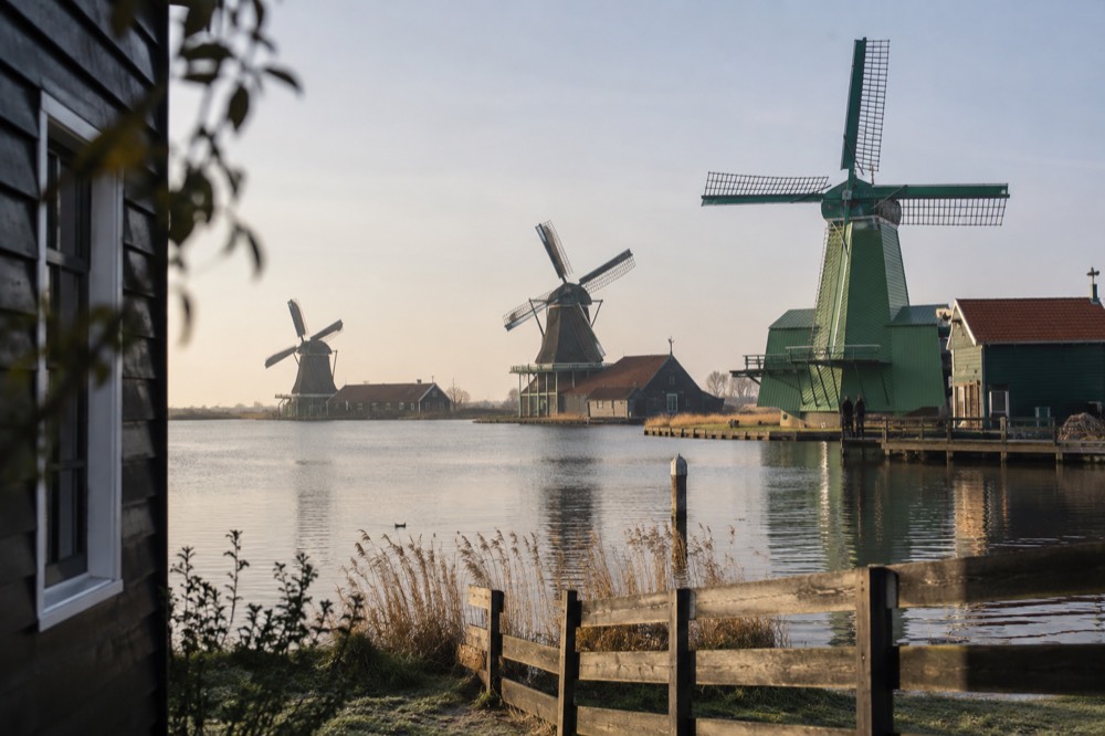 A row of historic windmills beside water at Zaanse Schans