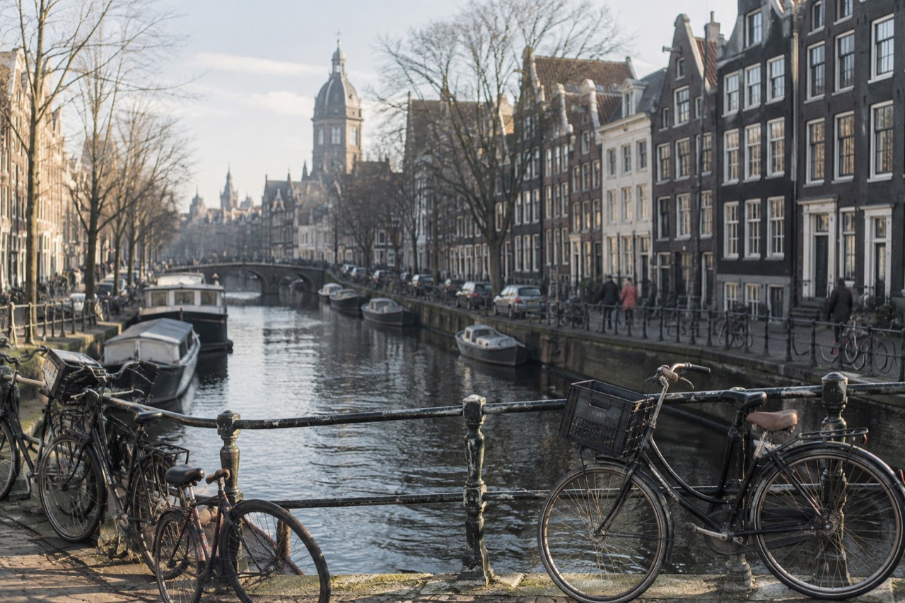 A canal in Amsterdam lined with gabled houses and bicycles on a bridge