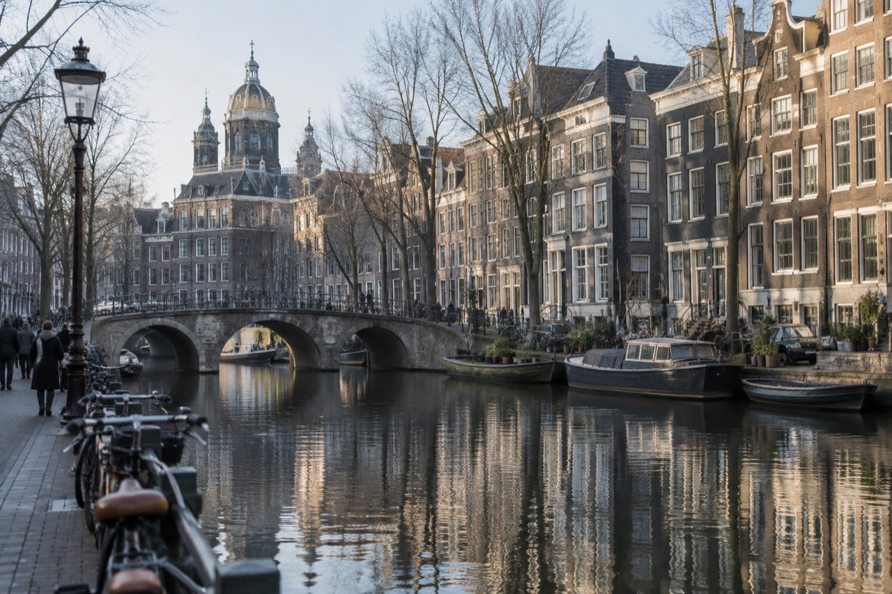 Amsterdam canal houses reflected in still water along the Grachtengordel at midday