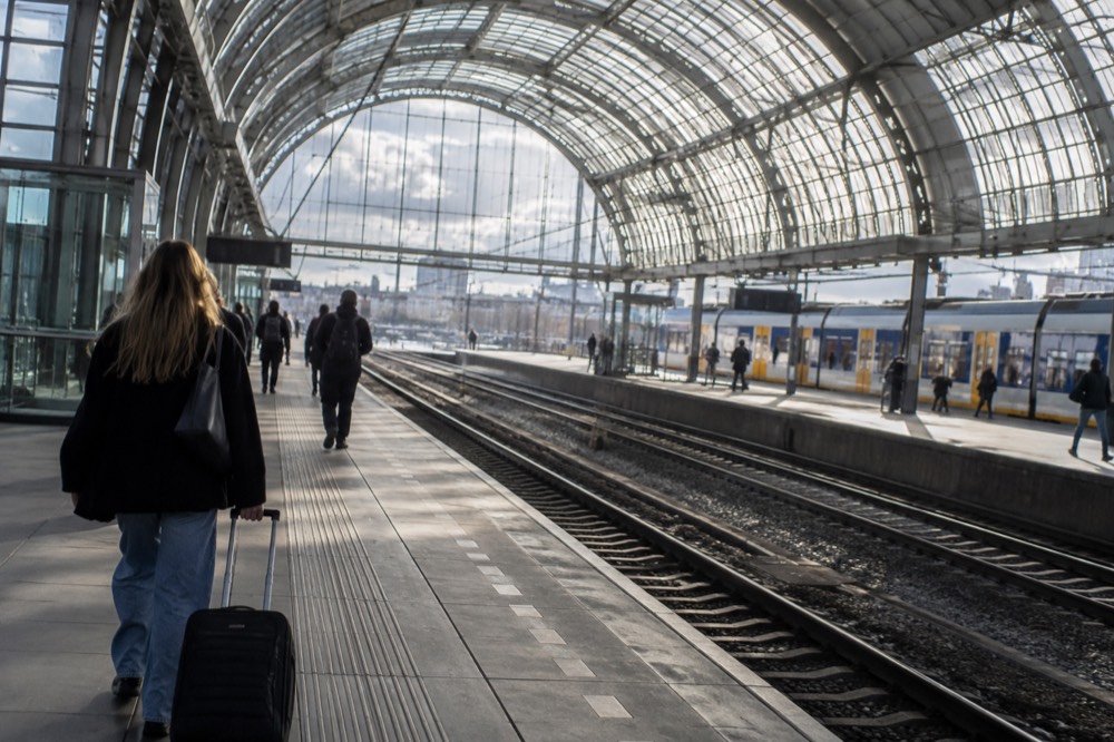 A train platform at an airport railway station beneath a large glass roof