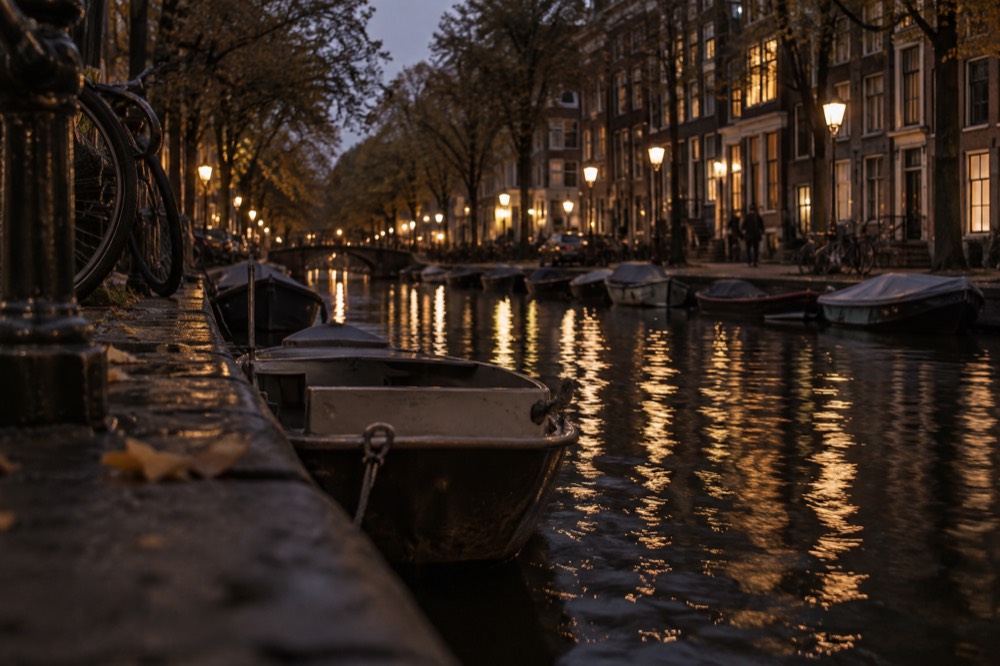 A quiet Amsterdam canal in the Jordaan with trees along the water and small boats