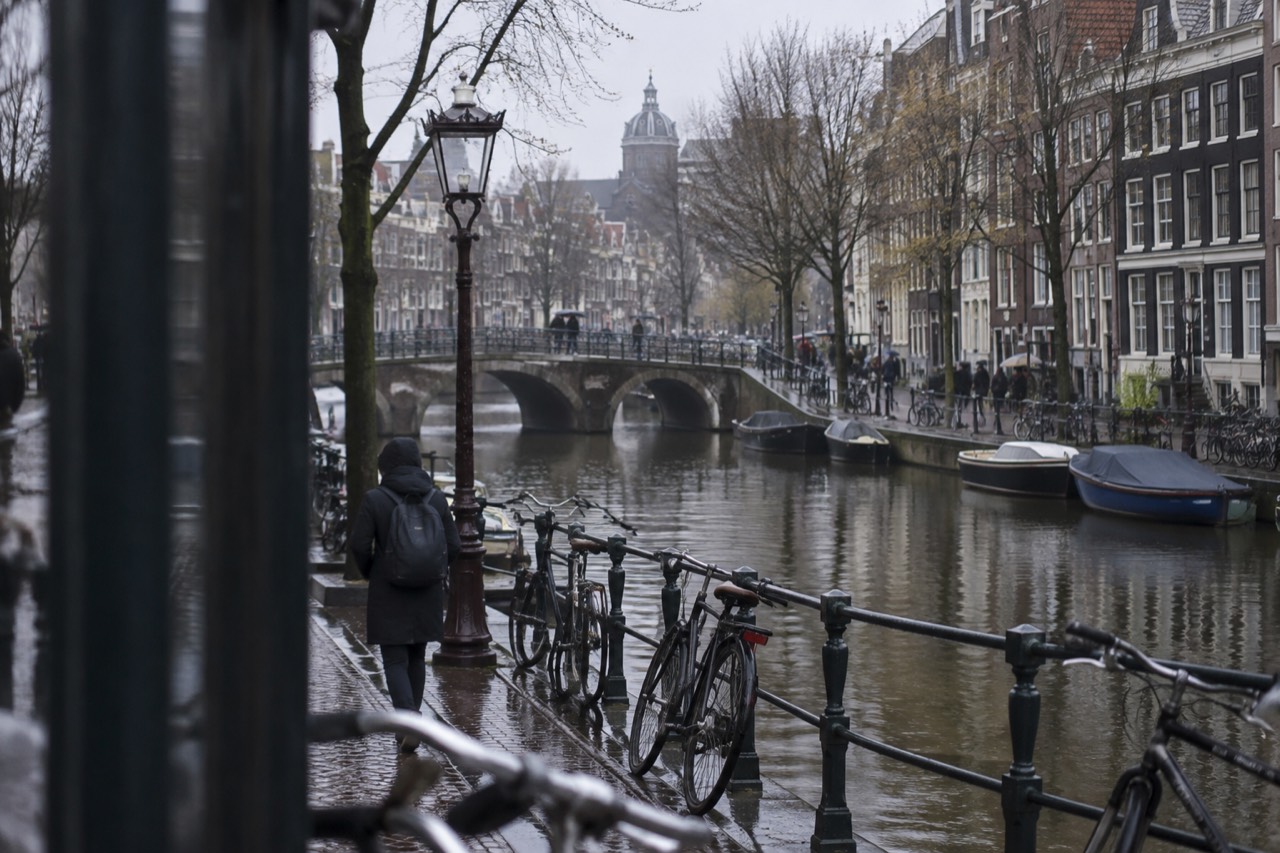 A canal in Amsterdam lined with narrow brick houses and moored bicycles