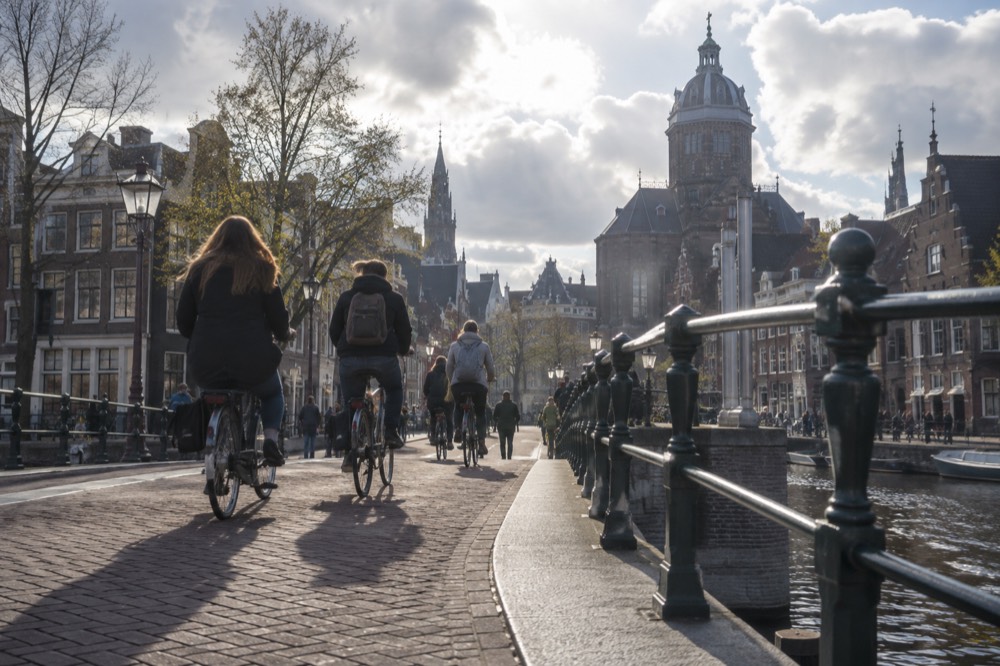 Cyclists crossing a canal bridge in daylight traffic