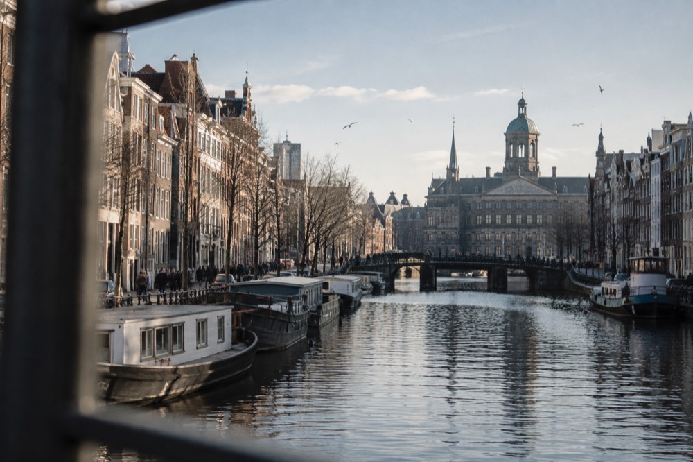 The Damrak canal in Amsterdam lined with gabled buildings and moored boats leading toward Dam Square