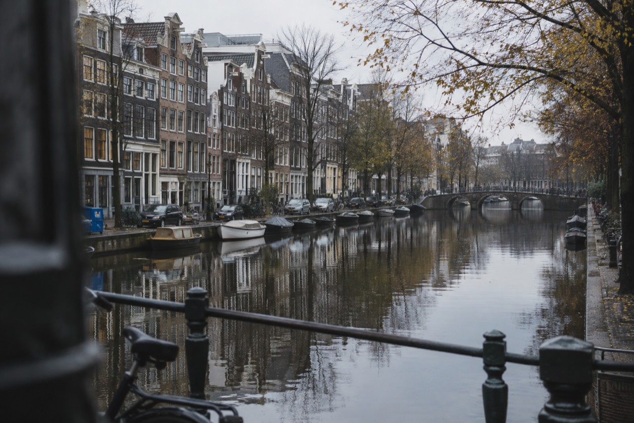 Amsterdam canal houses reflected in still water on a grey autumn morning