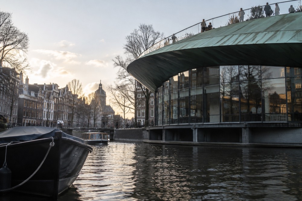 The curved green roof terrace of a modern museum building above a canal in Amsterdam