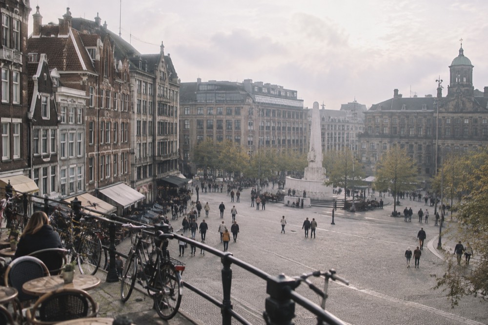 A residential Amsterdam street with bicycles parked against railings outside cafés