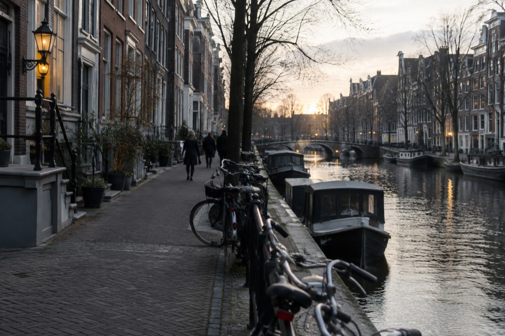 A quiet canal-side street with narrow brick houses and parked bicycles at dusk
