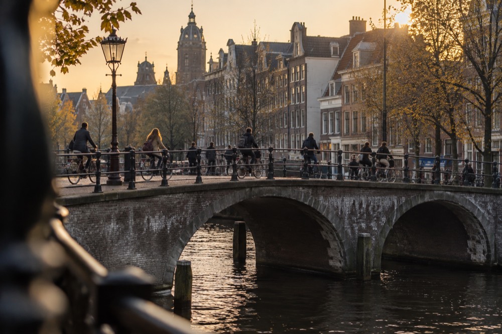 Cyclists crossing a canal bridge in central Amsterdam on a busy afternoon