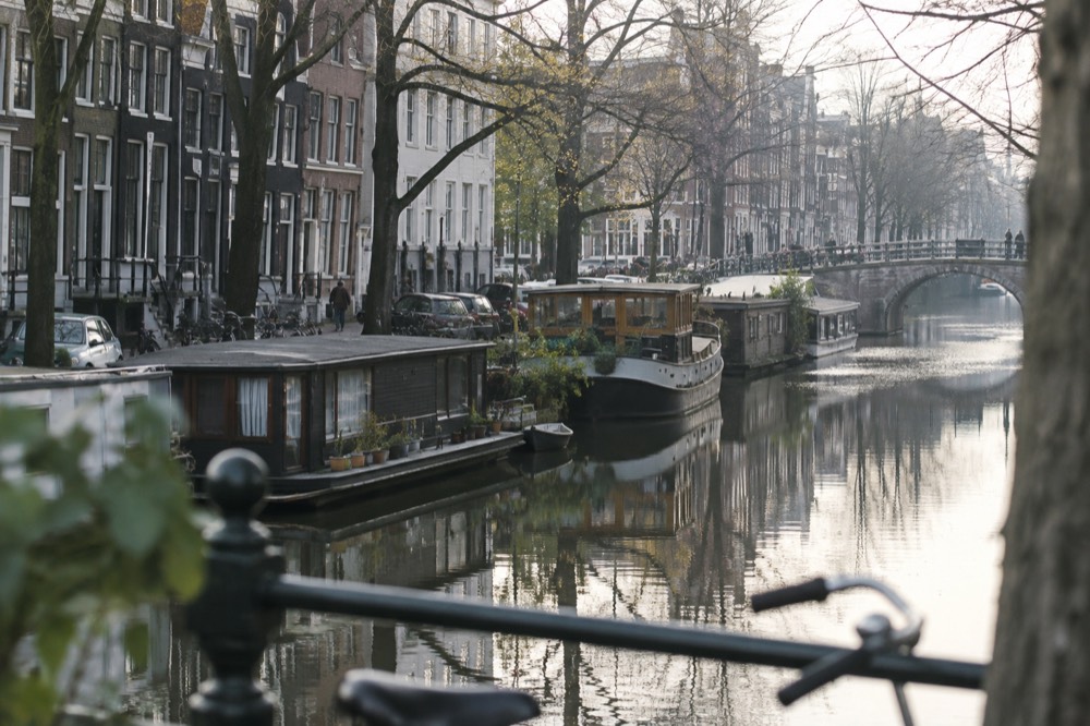 A canal in Amsterdam with houseboats and brick canal houses reflected in still water