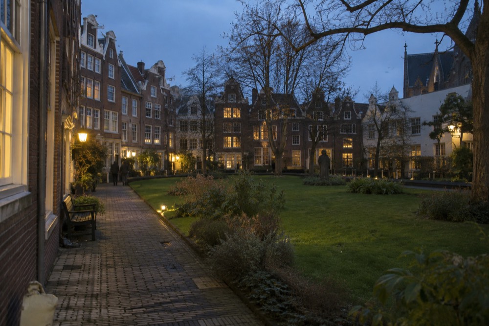 A hidden garden courtyard with small brick houses and a lawn enclosed by taller buildings