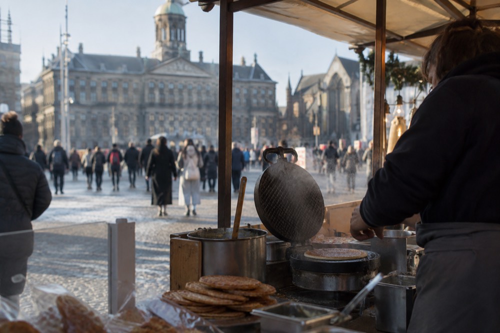 A market stall pressing fresh stroopwafels with steam rising from the waffle iron