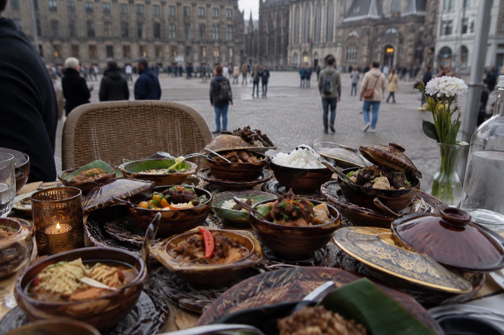 An Indonesian rijsttafel table filled with many small covered dishes of food