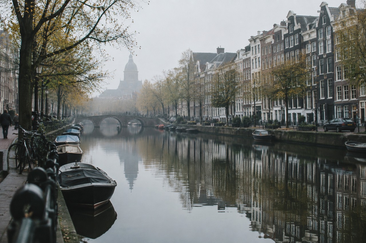 Amsterdam canal houses reflected in still water on a quiet morning