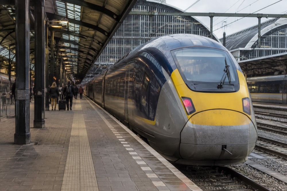 A Eurostar train at Amsterdam Centraal platform with the destination board showing Brussels and Paris.