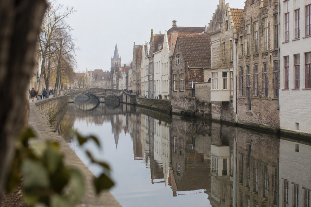 A long canal in Bruges with brick houses reflected in still water