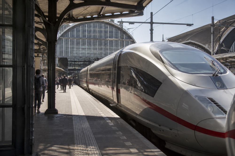 A high-speed train standing at a platform beside a station hall