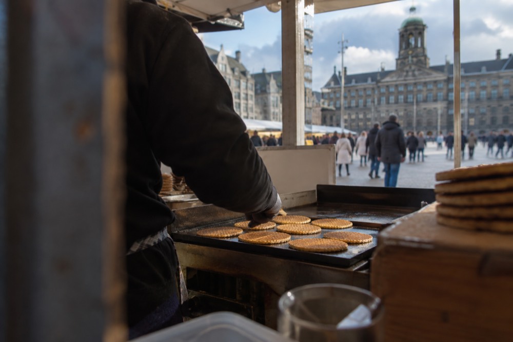 Freshly made stroopwafels cooling on a hot griddle at an Amsterdam market stall