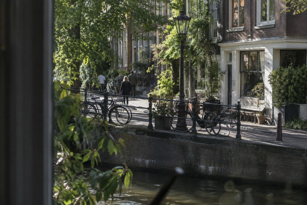 A quiet Jordaan side street with small shops and bicycles parked along a canal railing