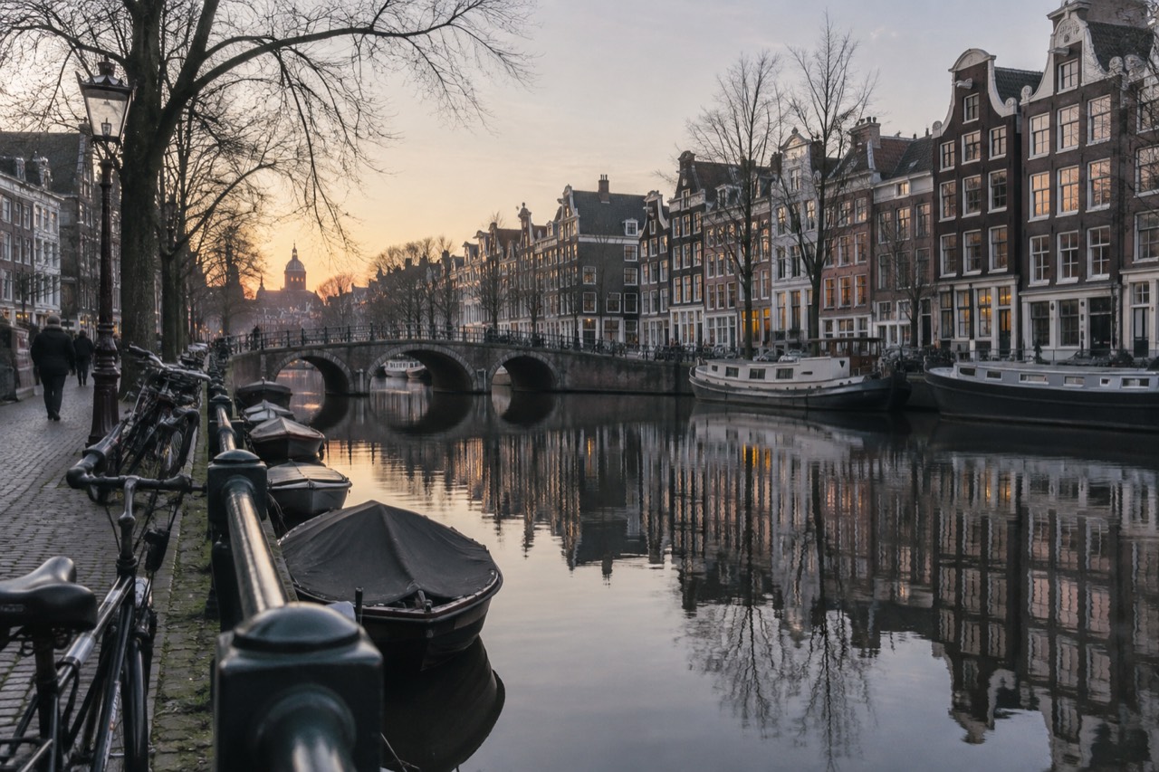 Amsterdam canal houses reflected in still water along the Grachtengordel at dusk