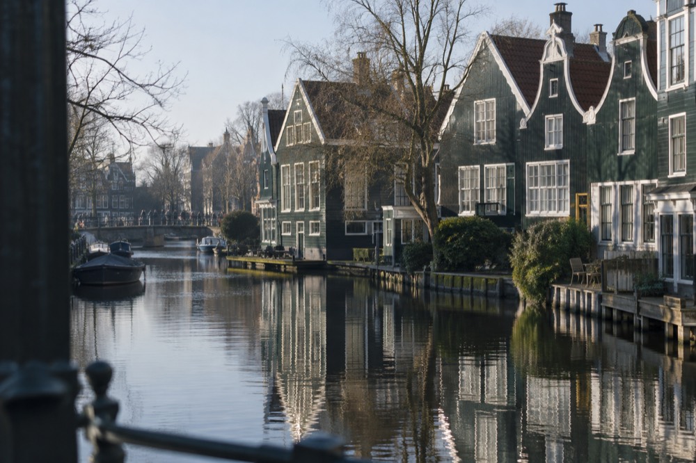 Traditional green wooden houses with white-framed windows along a calm Dutch river
