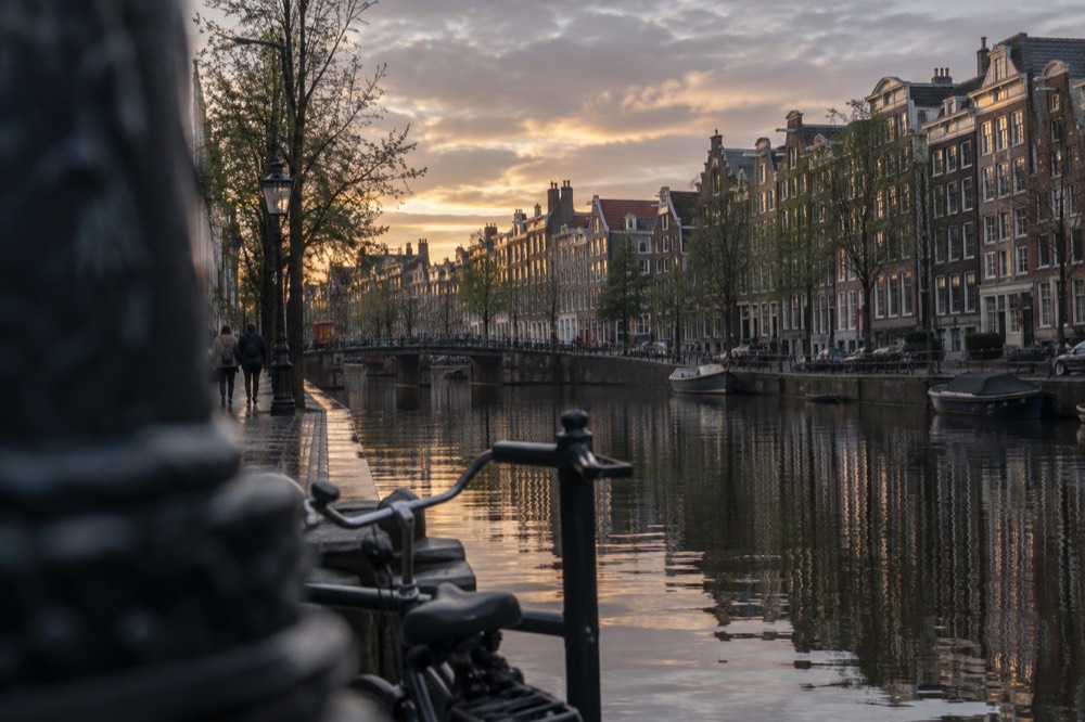 Sunset light on a row of narrow Amsterdam canal houses reflected in the water