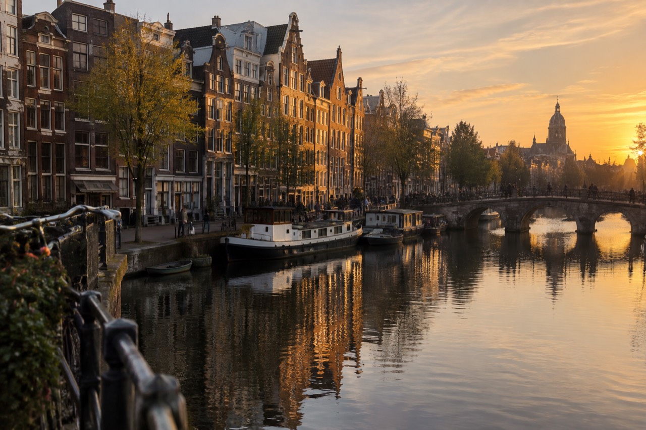 Amsterdam canal houses glowing in warm evening light above still water