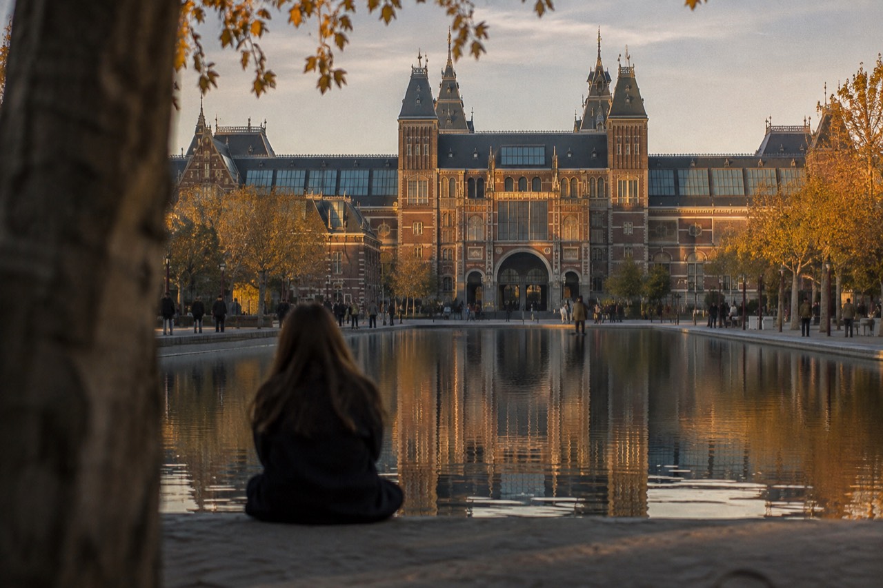 The historic Rijksmuseum building reflected in the water of Museumplein at dusk