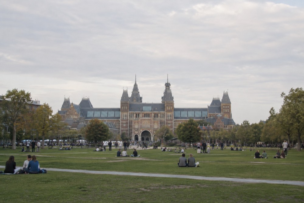 Museumplein square in Amsterdam with the Rijksmuseum building and visitors on the lawn