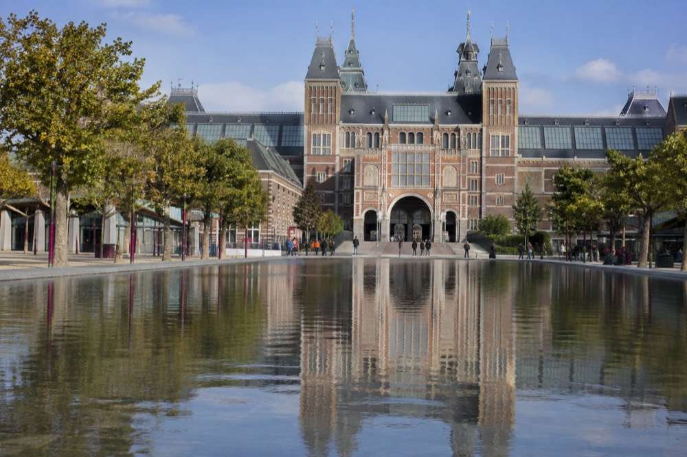 The Rijksmuseum facade reflected in the shallow pool on Museumplein
