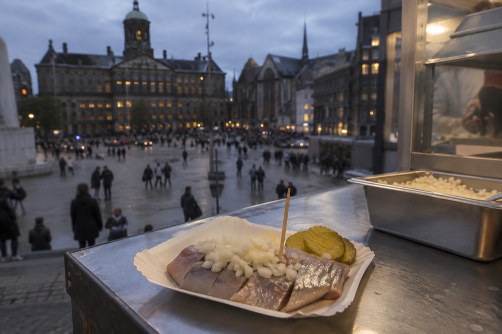 Fresh herring served with chopped onion at a market stall counter