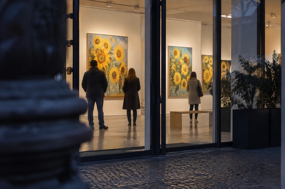Visitors viewing sunflower paintings in a bright modern gallery