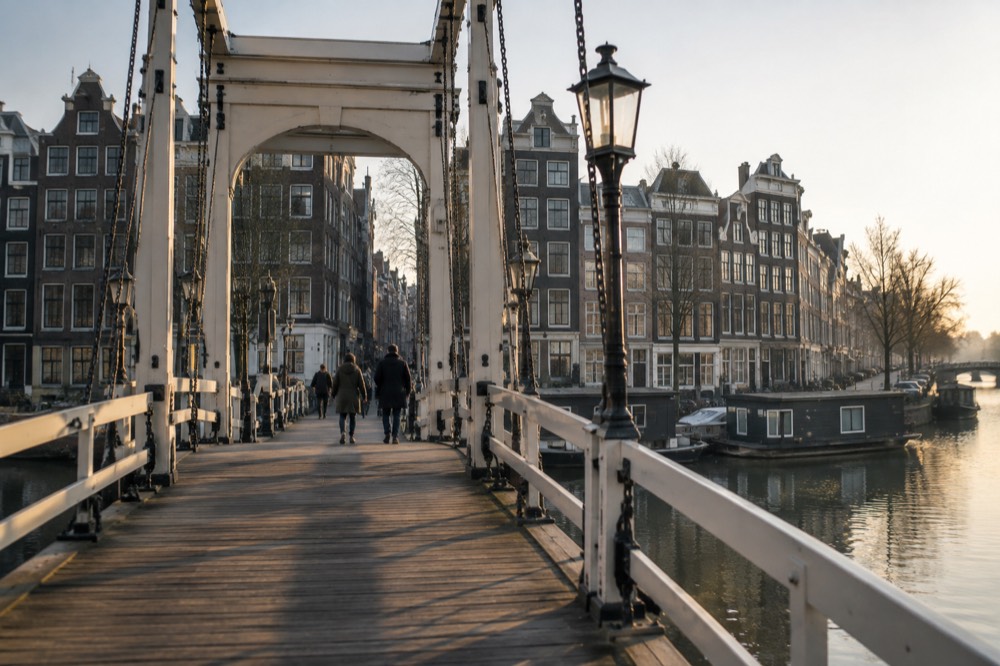 Wooden drawbridge over the Amstel river with classic Amsterdam facades behind it