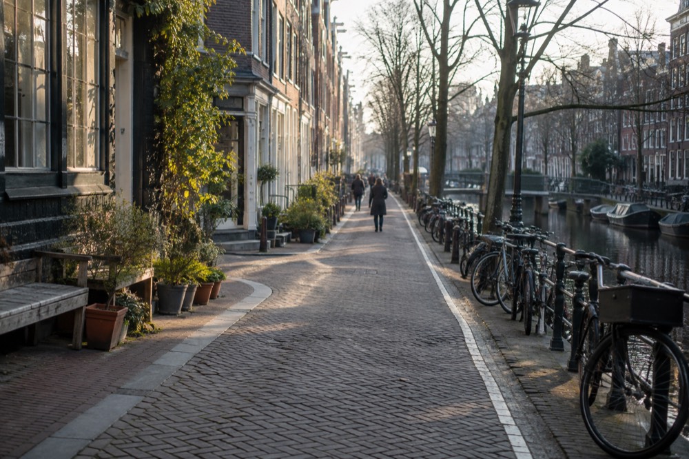 Narrow Jordaan street with small shops and bicycles leaning against canal railings