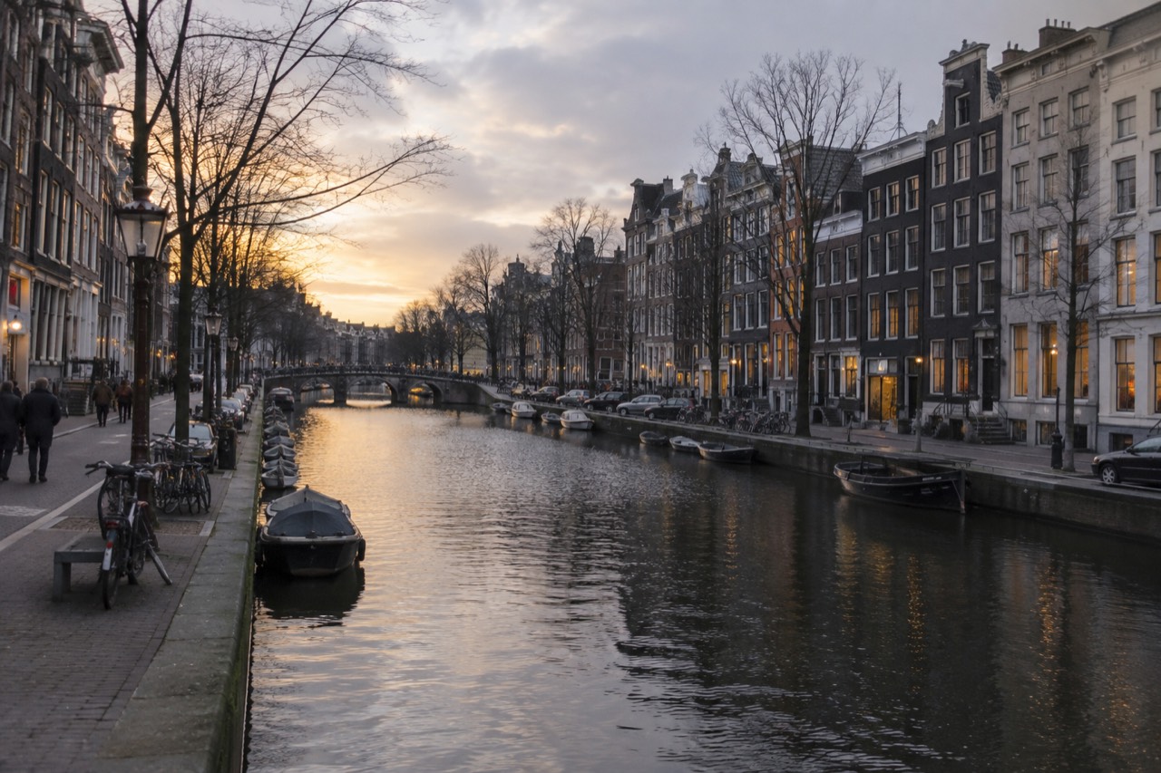 Canal houses and shop fronts along an Amsterdam canal at dusk