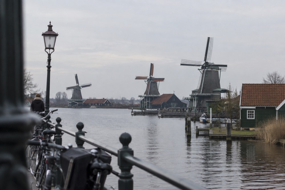A row of historic windmills standing beside a canal under a wide sky
