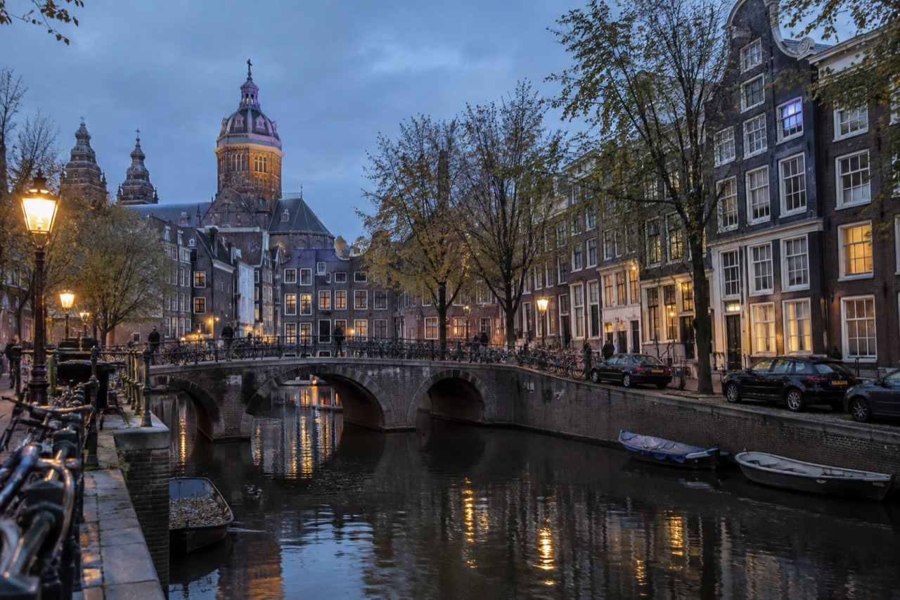 A quiet canal village with wooden bridges and thatched cottages reflected in still water
