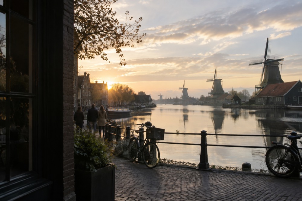 Historic windmills reflected in still canal water at sunrise