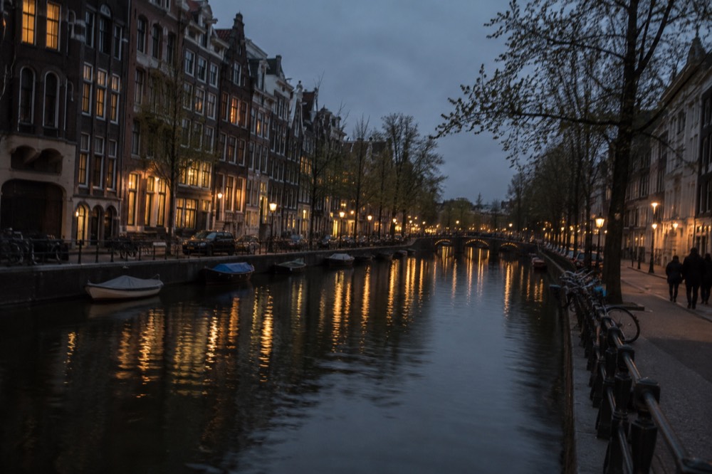 A canal-side street in central Amsterdam with narrow gabled houses reflected in the water