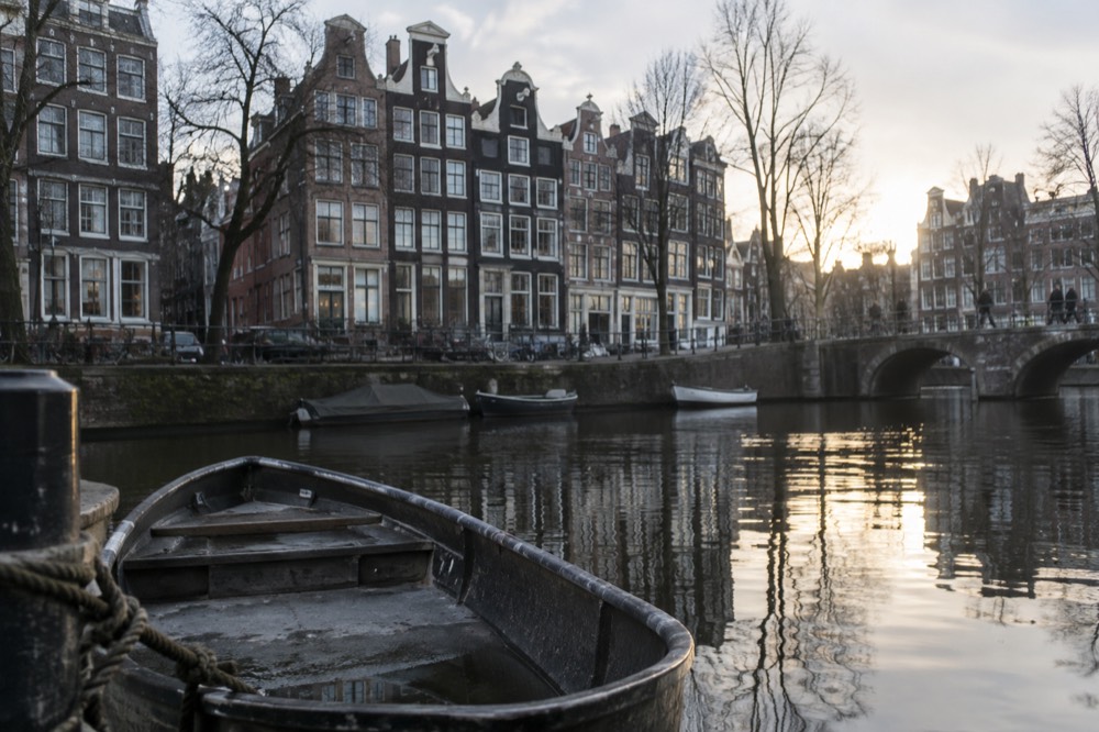 Row of narrow gabled canal houses reflected in an Amsterdam canal