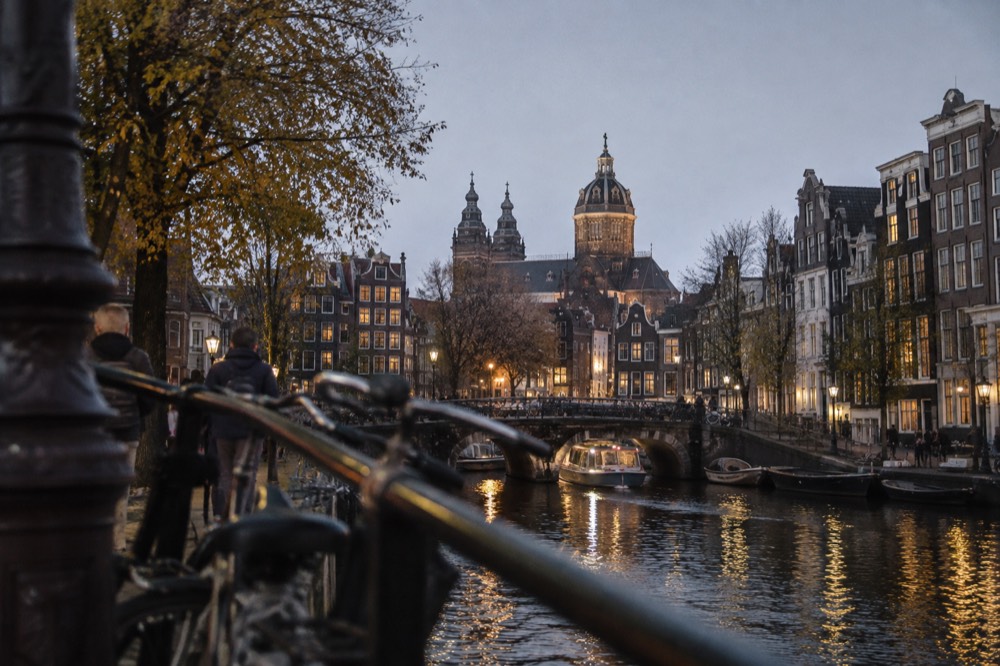 Evening view of a canal lined with narrow gabled houses and lit windows