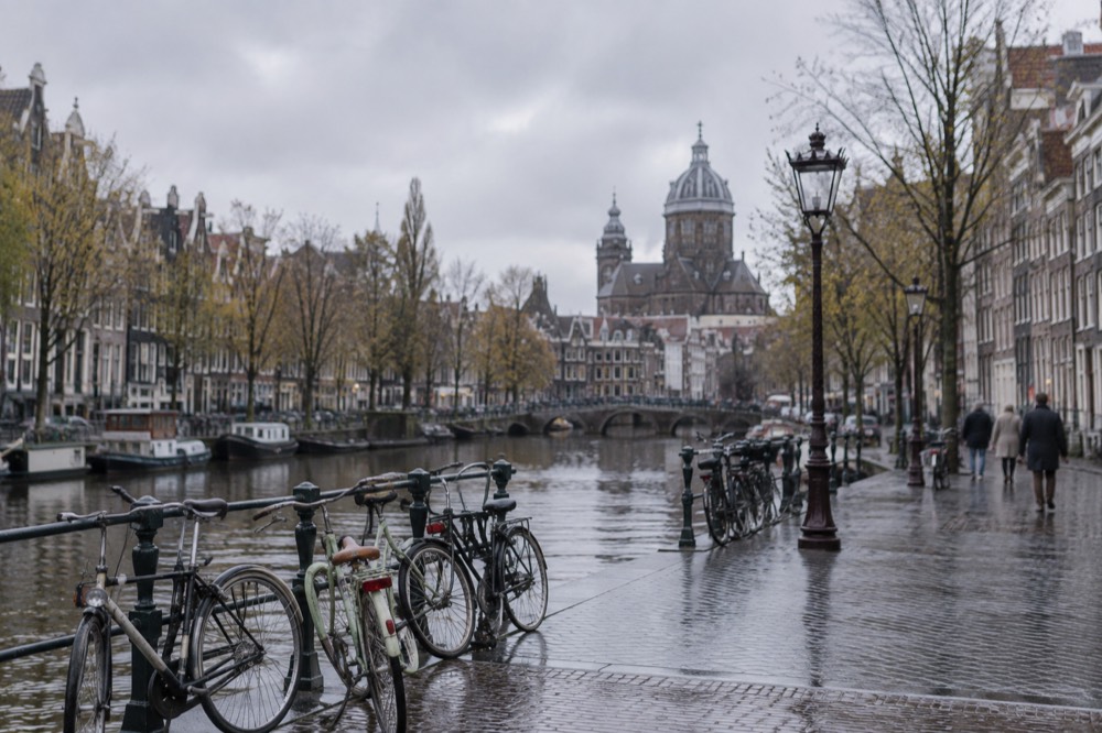A quiet canal-side street with bicycles parked against railings in daylight
