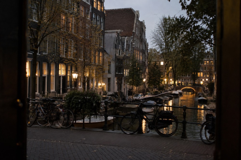 Narrow canal in the Amsterdam city centre lined with gabled brick houses and bicycles