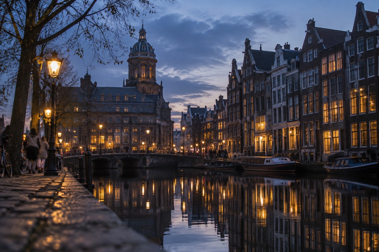 Amsterdam canal houses reflected in still water at dusk