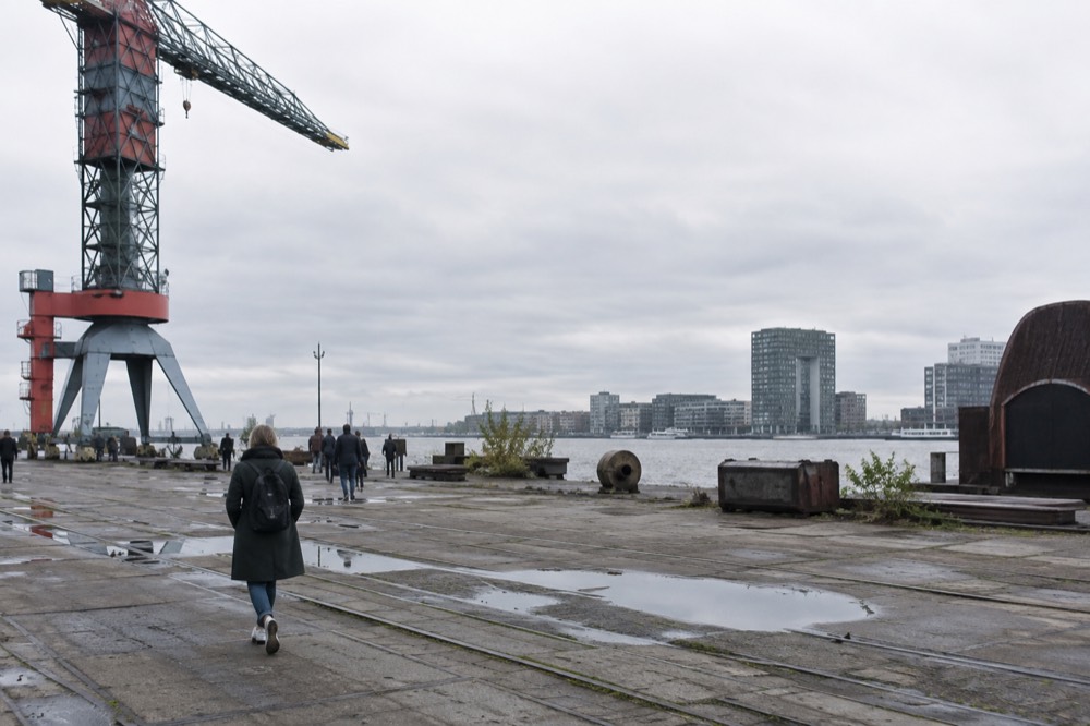 People walking past NDSM Wharf, seen from across the street