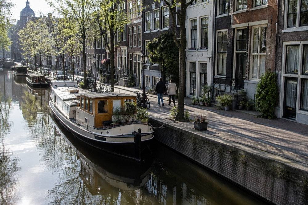 Canal boat moored beside a quiet residential street with narrow gabled houses