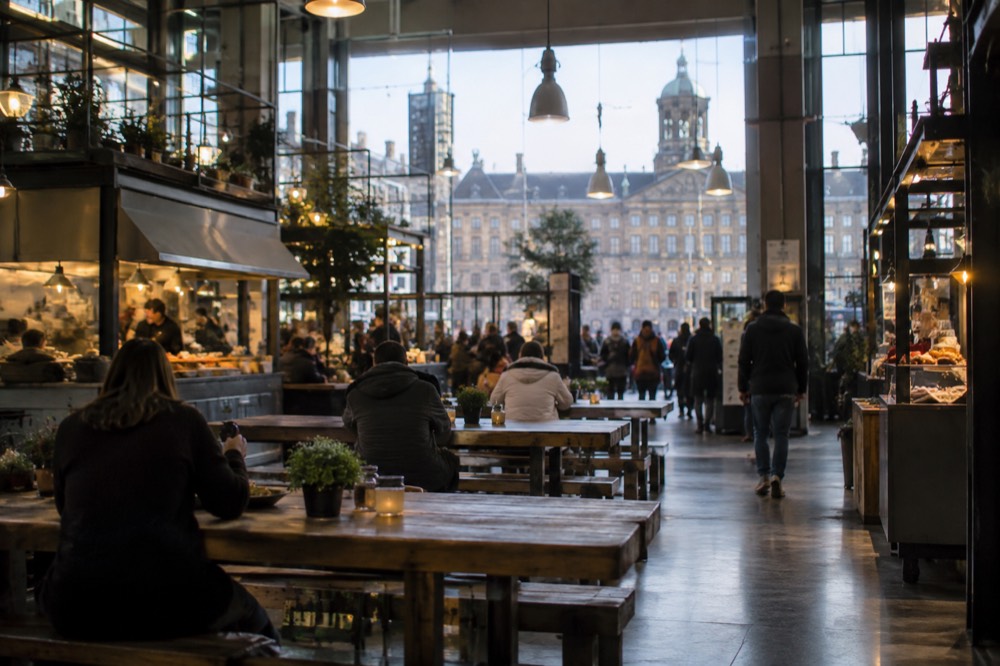 Indoor food hall with wooden benches, food stalls and hanging lights
